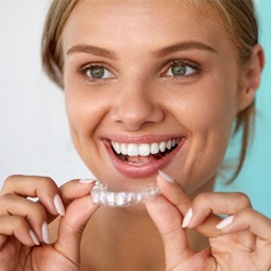 woman smiling holding Invisalign